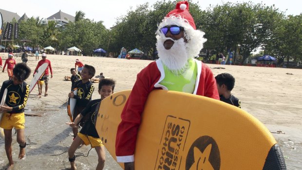 An Indonesian surf instructor dressed as Santa Claus at Kuta beach in Bali, Indonesia.