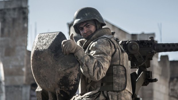 A Turkish soldier gives the thumbs up on Sunday on top of an army vehicle in Kobane.