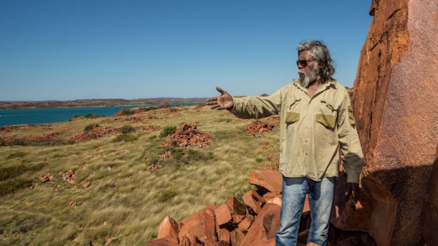 Senior cultural ranger at Murujuga National Park, Jakari Togo, looks out to sea next to rock carvings on the Burrup Peninsula.