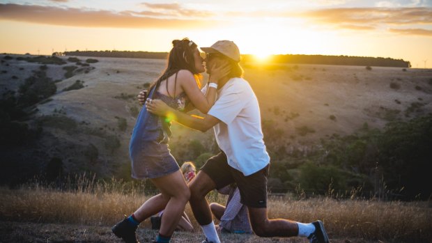 A couple is engaged at Golden Plains at sunset.