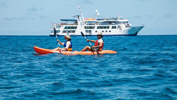 Kayakers with expedition ship Isabela II behind them.