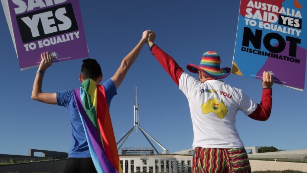 Supporters of same-sex marriage pose for photographers with the rainbow flag during a rally on the front lawn of Parliament.