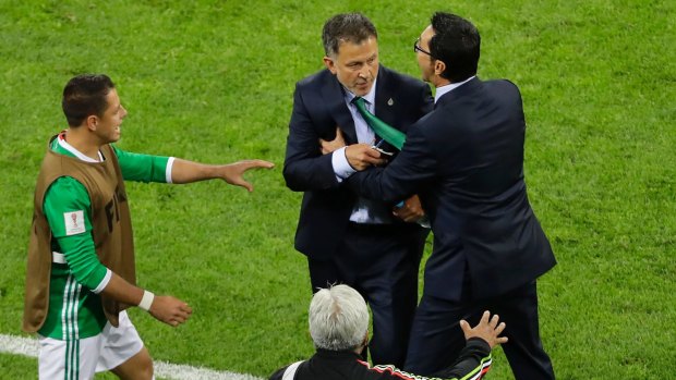 Mexico coach Juan Carlos Osorio is restrained after swearing at the New Zealand bench.