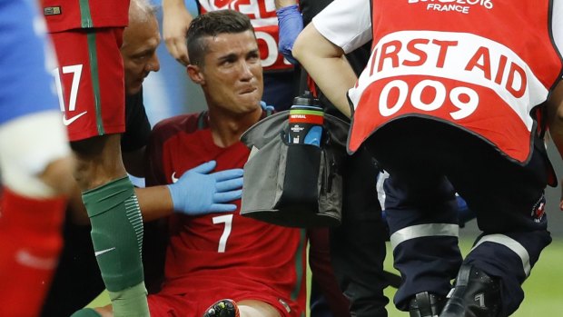 Cristiano Ronaldo sits on the pitch in pain moments before being carried  off the pitch.