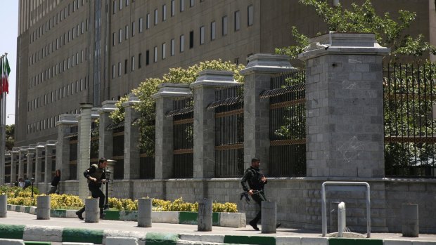 Police officers run to take position around Iran's parliament building following an assault by several attackers on Wednesday.