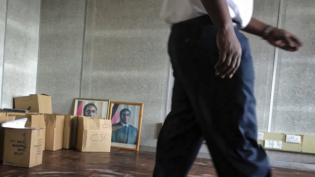 A worker walks past photographs of  Robert Mugabe at a government building in Harare.