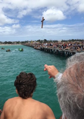 Father Eleftherios Tatsis tosses the cross into the water.