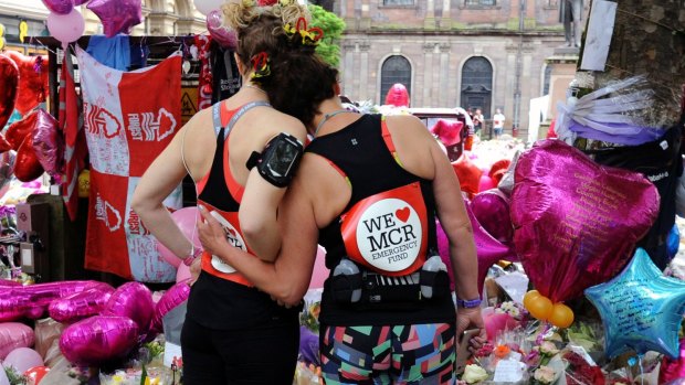 Marathon runners stop to pay their respects on Sunday at a tribute to the murdered victims of the Manchester bombing.