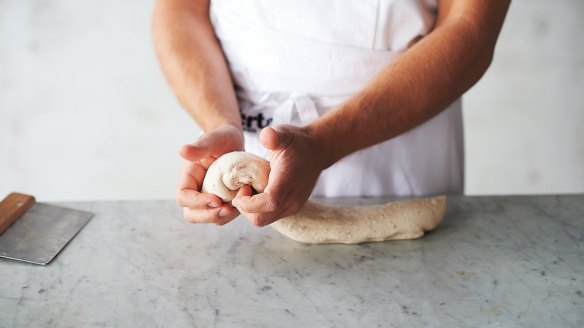 Shaping the dough step 2: The dough will feel soft, airy and malleable. Take the piece of dough at one end and, using both hands, form a ball about 200-250g in size. Work by tucking the folds under the ball so that the top surface is taut and smooth.