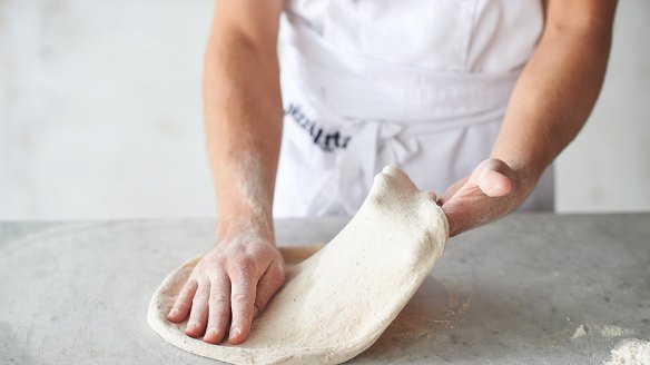 Shaping the base step 7: Keeping one hand on one side of the base, gently stretch the opposite side with the other hand and lift and slap the dough circle from side to side. This will stretch the gluten in the dough and the base will get larger and larger.