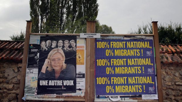 An election board with France's far-right Front National  leader, Marine Le Pen, and an anti-immigration poster.