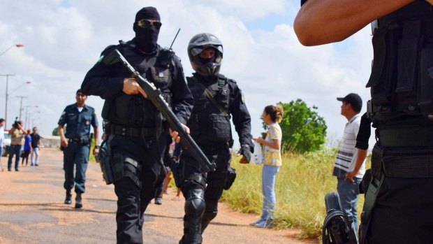 Heavily armed police officers walk outside the Agricultural Penitentiary of Monte Cristo, after dozens of inmates were killed, in Boa Vista, Roraima state, Brazil.