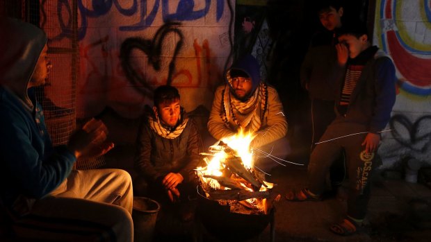 Palestinians, who get only several hours of electricity a day, sit around a fire outside their home in Gaza City. 