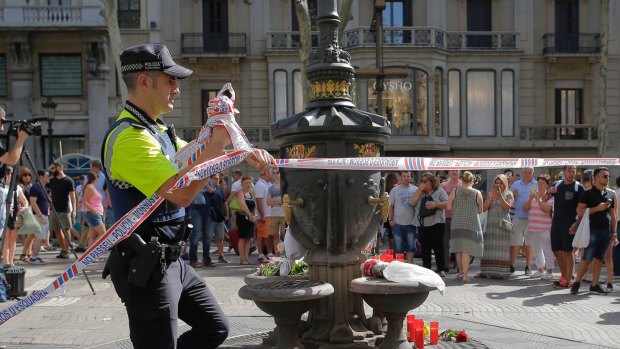 Returning to normal: A police officer removes police tape in Las Ramblas, Barcelona on Friday afternoon.