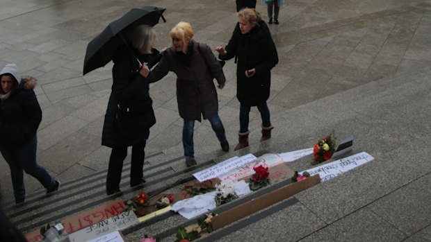 People stand in front of posters and flowers near the main train station in Cologne on Monday. 