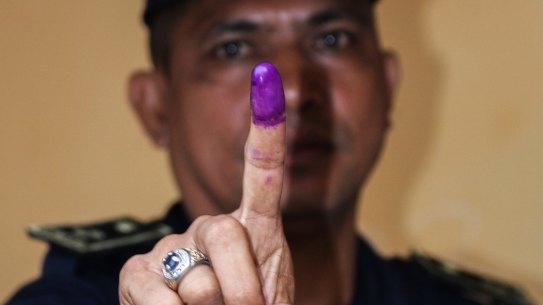A National Police officer shows his finger after voting in Farol, Dili, on Monday.
