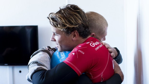 Julian Wilson (in red) hugs Mick Fanning, who was attacked by a shark during the fInal of the J-Bay Open on Sunday.