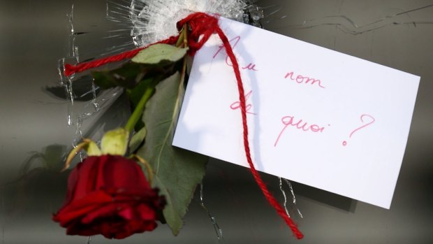 A rose in a bullet hole with a note that translates to "In the name of what?" at La Belle Equipe cafe. 