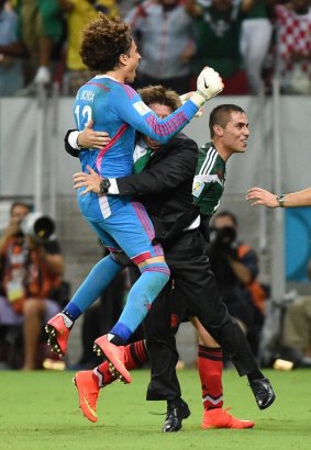 Sharing the excitement ... Mexico's coach Miguel Herrera (centre) hugs/tackles outstanding goalkeeper Guillermo Ochoa in celebration after another strong performance. 