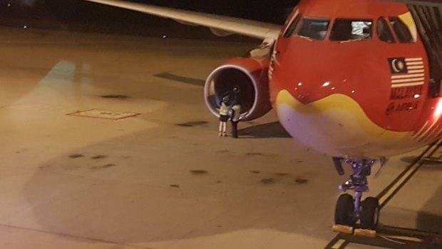 Groundstaff next to the engine of Air Asia X flight D7207 after it was diverted to Brisbane Airport.