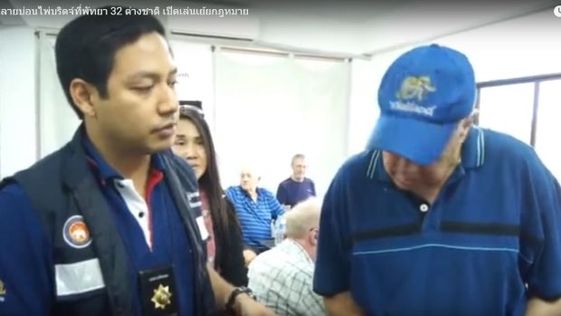 An elderly bridge player is questioned by a Thai policeman at a Jomtien and Pattaya Bridge Club meeting in Pattaya.