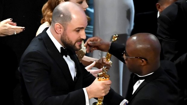 <i>La La Land</i> producer Jordan Horowitz, left, hands over the best picture award to <i>Moonlight</i> writer-director Barry Jenkins.
