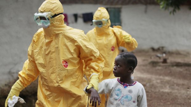 A young girl is taken to an ambulance after showing signs of the Ebola infection in Liberia during the 2014 outbreak.