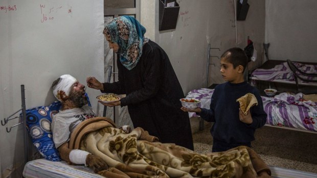Kawther al-Obaid feeds her husband, who was wounded in an air strike on Raqqa, as their son Bassam looks on at a hospital in Tal Abyad, Syria.