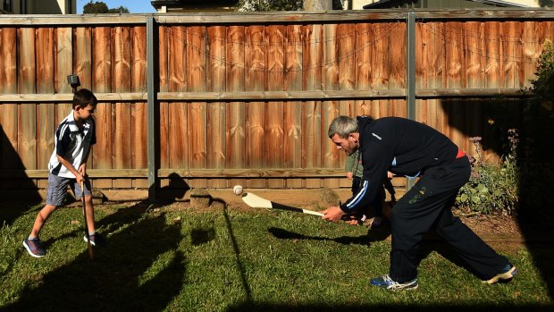 Sydney Shamrocks hurler Damien Moroney teaches some of the skills and techniques of hurling to his son Ciaran Moroney in their backyard in St Mary's.