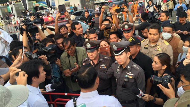 A media scrum forms around senior police at the temple.