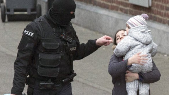 Police evacuate a woman and a small child during a police raid targeting Paris attacks suspect Salah Abdeslam.