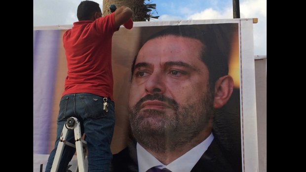 Workers hang a poster of former PM Saad Hariri in Beirut saying: "We are all Saad".