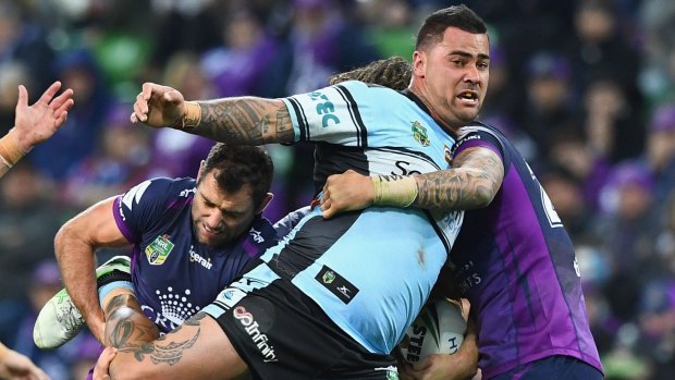 Hard to bring down: Cameron Smith hangs onto Andrew Fifita.