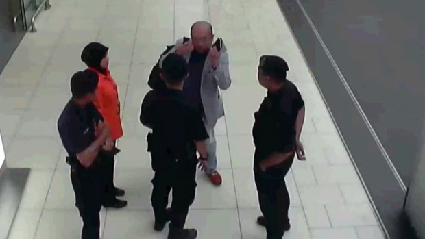 In this image made from security camera footage and provided by Fuji Television, Kim Jong-nam gestures towards his face while talking to airport security at Kuala Lumpur International Airport.