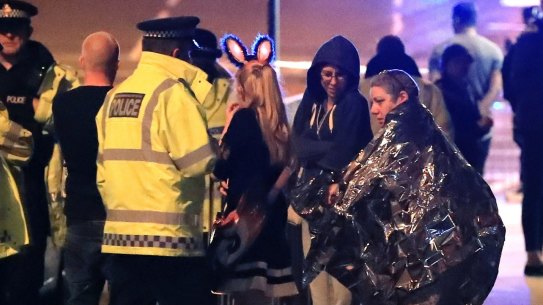 Emergency services personnel speak to people outside Manchester Arena after an explosion.