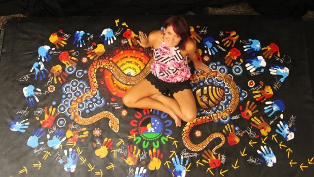 Chern'ee Sutton with one of her pieces for the  Indigenous All Star game. The piece will be auctioned off by the NRL to raise funds for AIME, an Indigenous Mentoring program.
