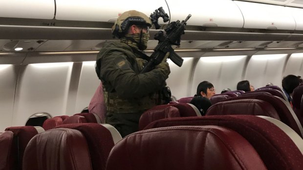 Security personnel board flight MH128 after it returned to Melbourne.