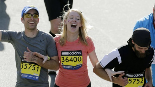 Timothy Haslet, left, and David Haslet, right, celebrate with their sister Adrianne Haslet-Davis as she crosses the finish line of the 118th Boston Marathon in Boston in 2014.