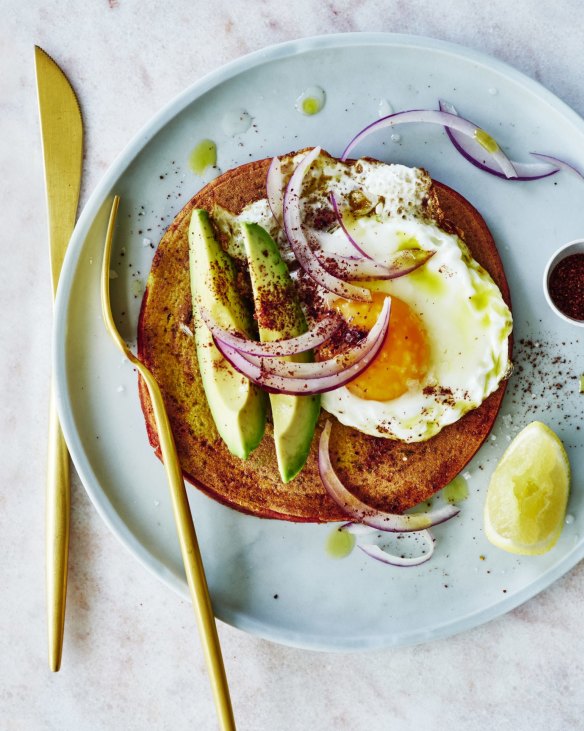 Chickpea pancakes topped with avocado, onion salad and a fried egg.