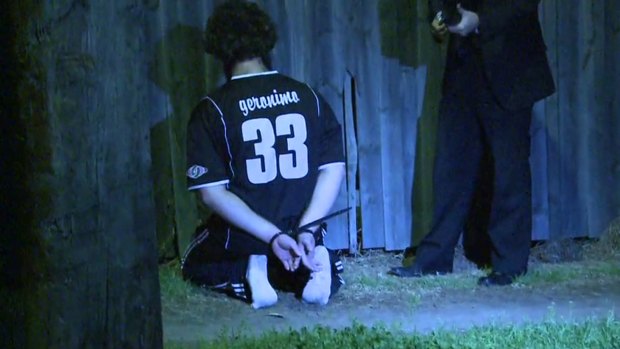 A man detained by police during a raid kneels on the ground in Sydney.