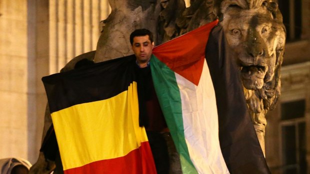 A man waves a Belgian and Palestinian flag as a mark of solidarity at the Place de la Bourse on Tuesday. 