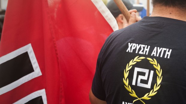 A protester wearing a Golden Dawn T-shirt, next to a swastika flag in Brisbane.