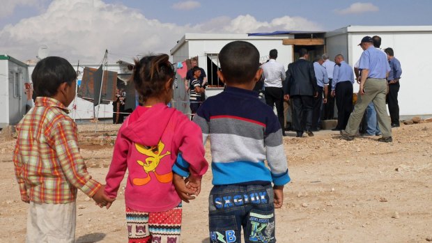Refugee children watch Immigration Minister Peter Dutton and entourage as they tour Zaatari refugee camp.