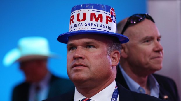 A delegate wears a hat with a campaign sticker for Donald Trump.