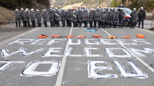 "Refugees wellcome to EU" is painted on a street in front of Austrian police officers gathered in the village of Brenner on the Italian-Austrian border on Sunday.
