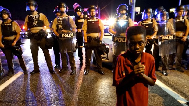 A young boy stands in front of a police line shortly before shots were fired.