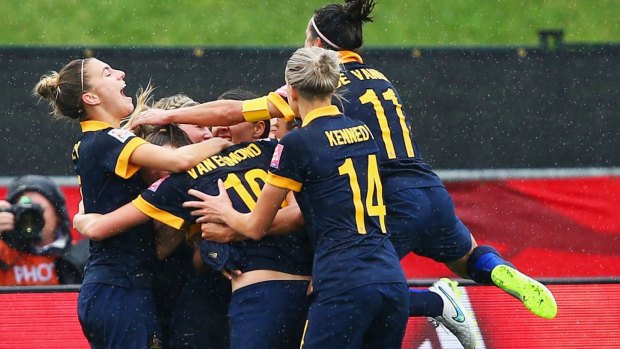 Kyah Simon of Australia (obscured) is mobbed by teammates after scoring the winning goal.