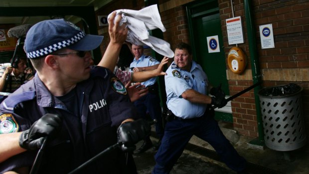 Craig Campbell, pictured with his baton, fends off violent youths during the Cronulla riots in 2005.