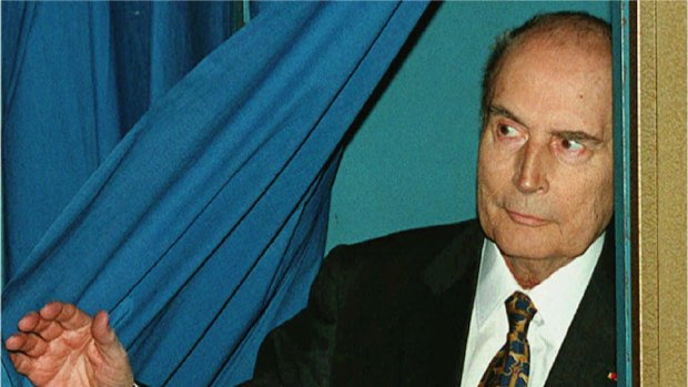 French Socialist President Francois Mitterrand leaves a polling booth holding his ballot in 1995.