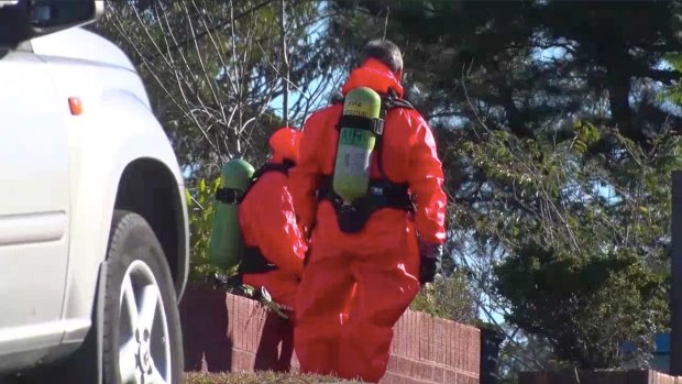 Hazmat specialists wear jumpsuits and oxygen tanks to examine the chemicals.